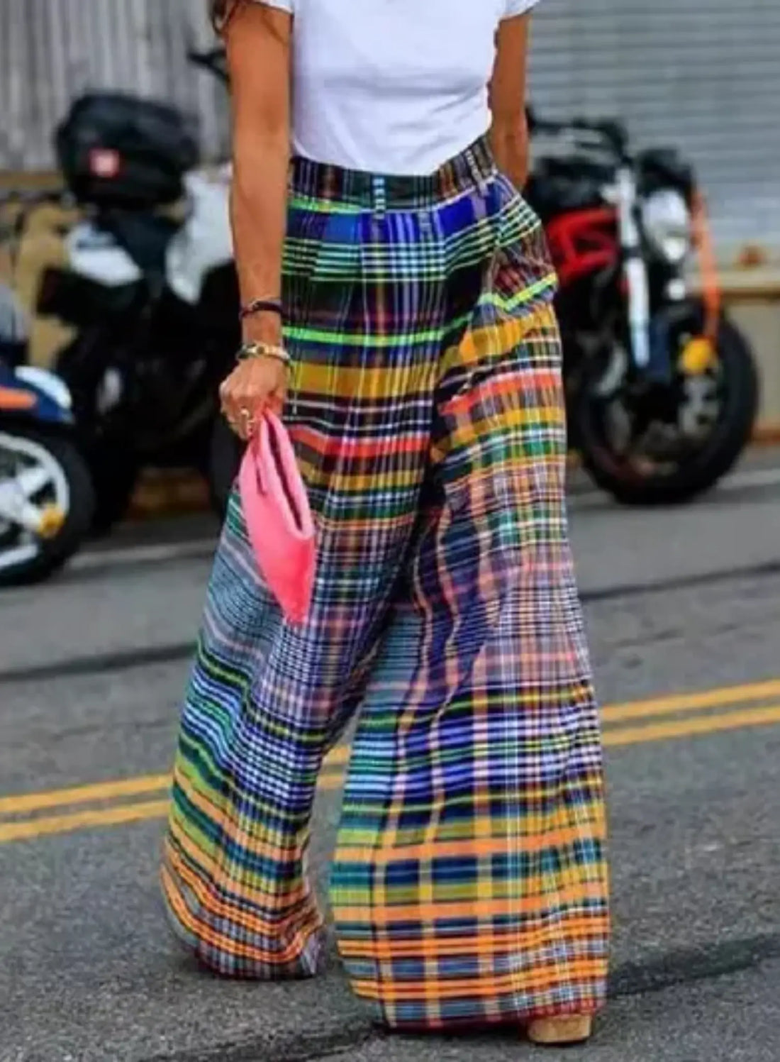 wide-legged, high-waisted, multi-colored plaid pants. The pants feature a vibrant pattern with a mix of bold colors, including yellow, red, blue, and green, creating a statement look.